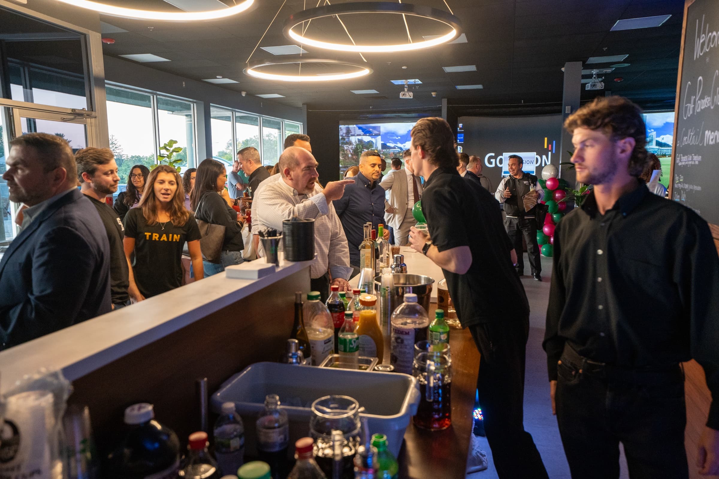 Corporate event guests gathering by the bar at Golf Paradise Club