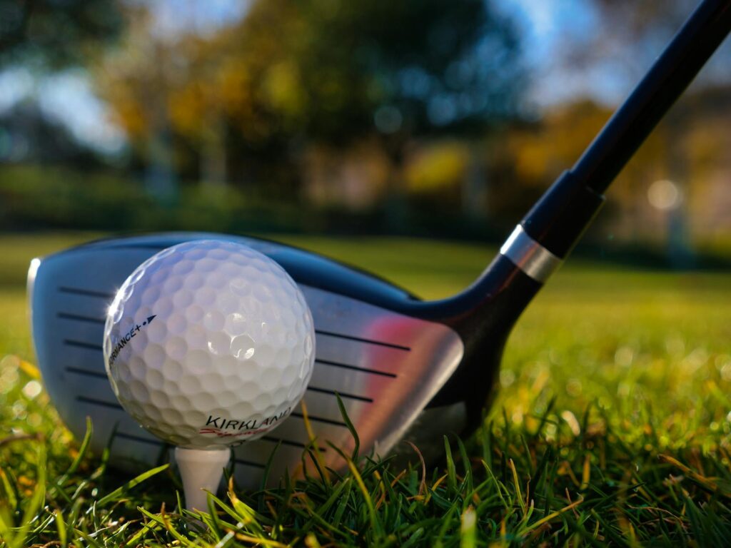 Detailed close-up of a golf ball and club on lush green grass. Perfect for sports enthusiasts.